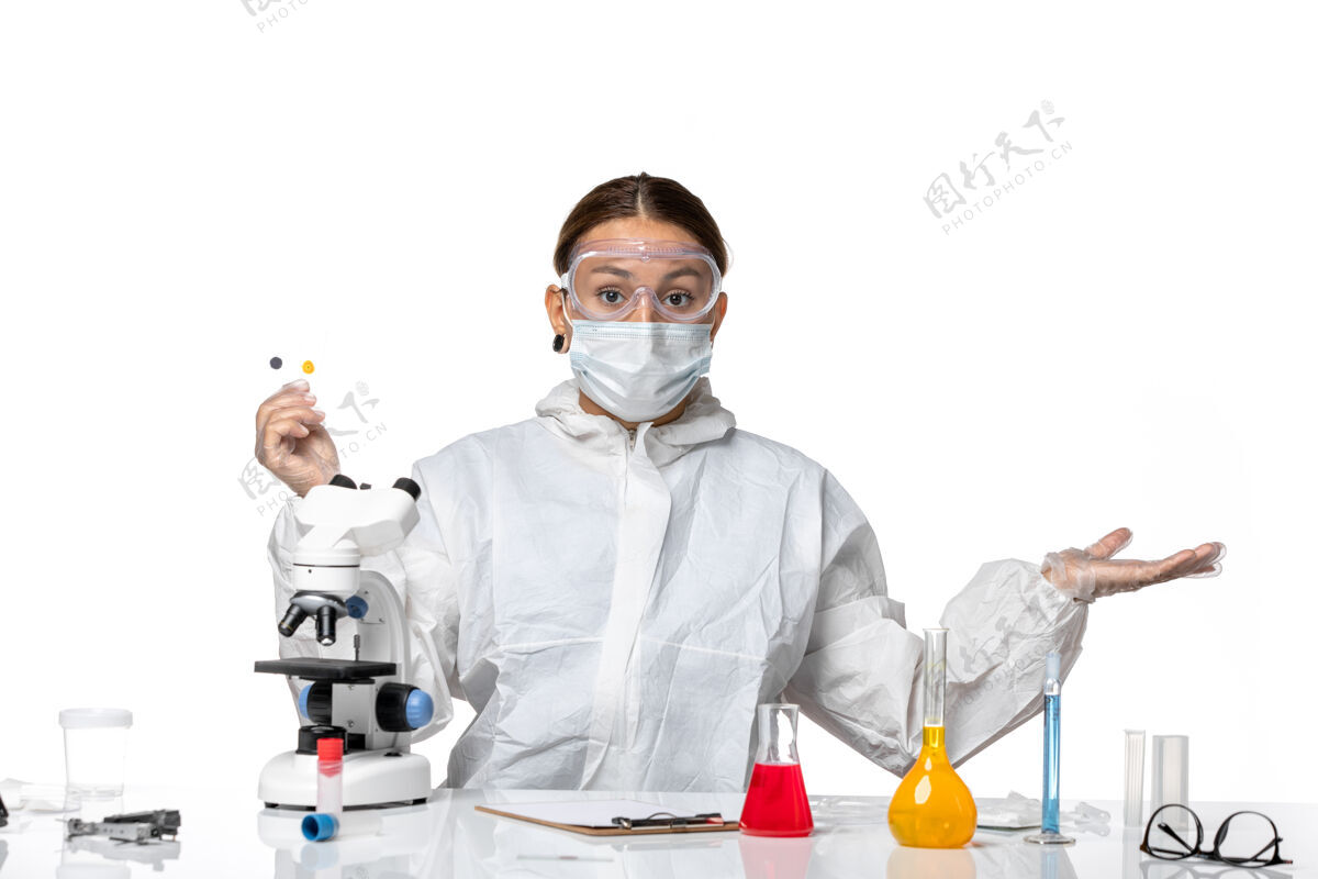 面罩正面图女医生穿着防护服 戴着口罩拿着小样本 背景是白色的医药卫生大流行病毒冠状病毒样品展示视图