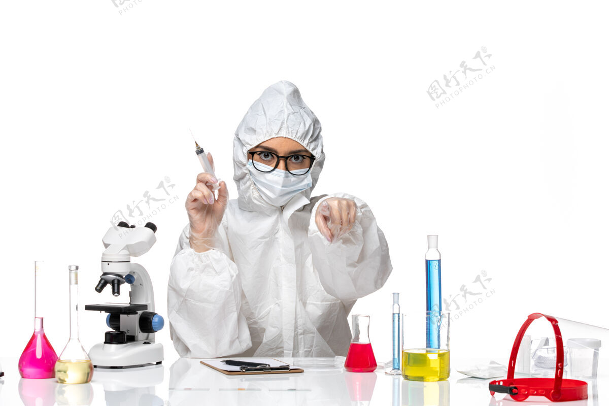 面罩前视图穿着特殊防护服的女化学家手持白色背景化学冠状病毒大流行的注射剂白色医生医院