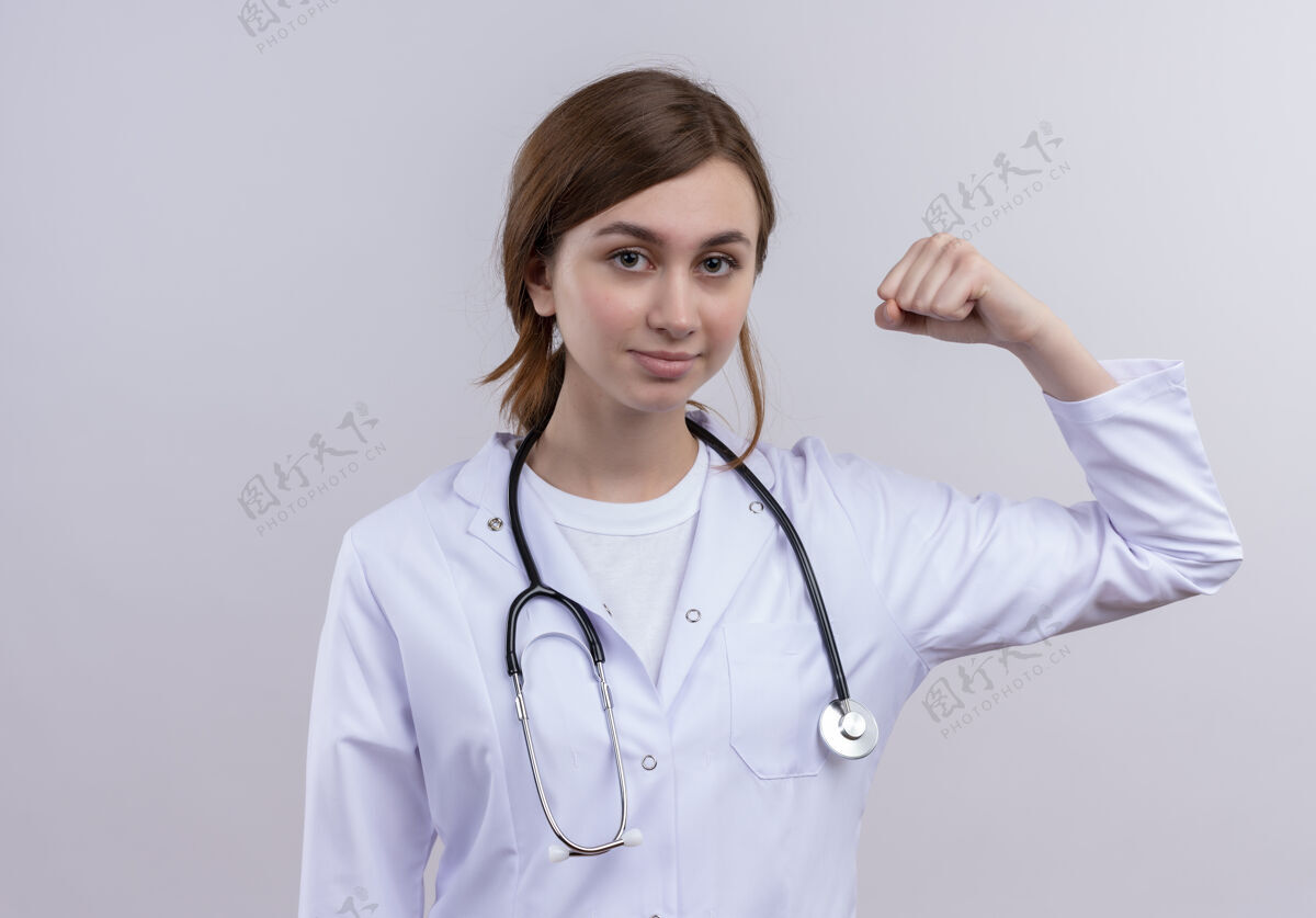 强壮自信的年轻女医生穿着医用长袍和听诊器做着坚强的手势医生长袍女性