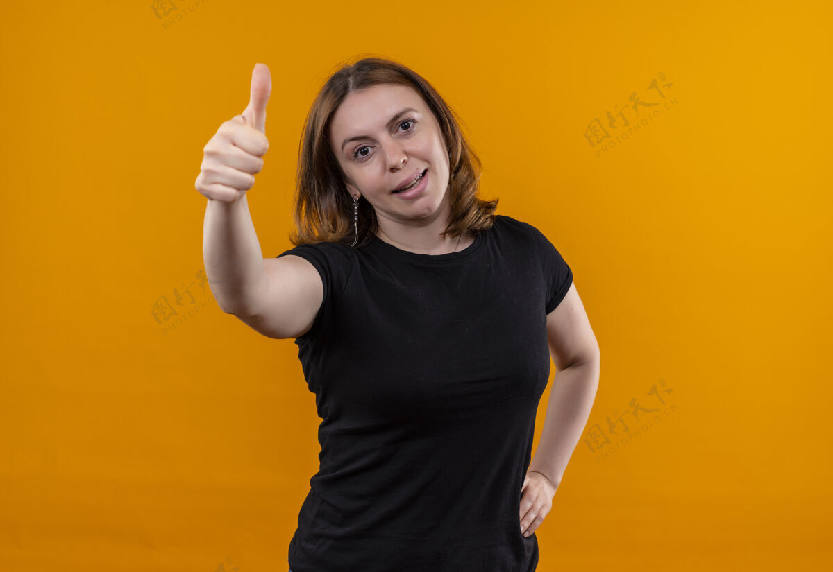 显示自信的年轻休闲女性 手放在腰上竖起大拇指 在孤立的橙色空间和复制空间复制大拇指橙色