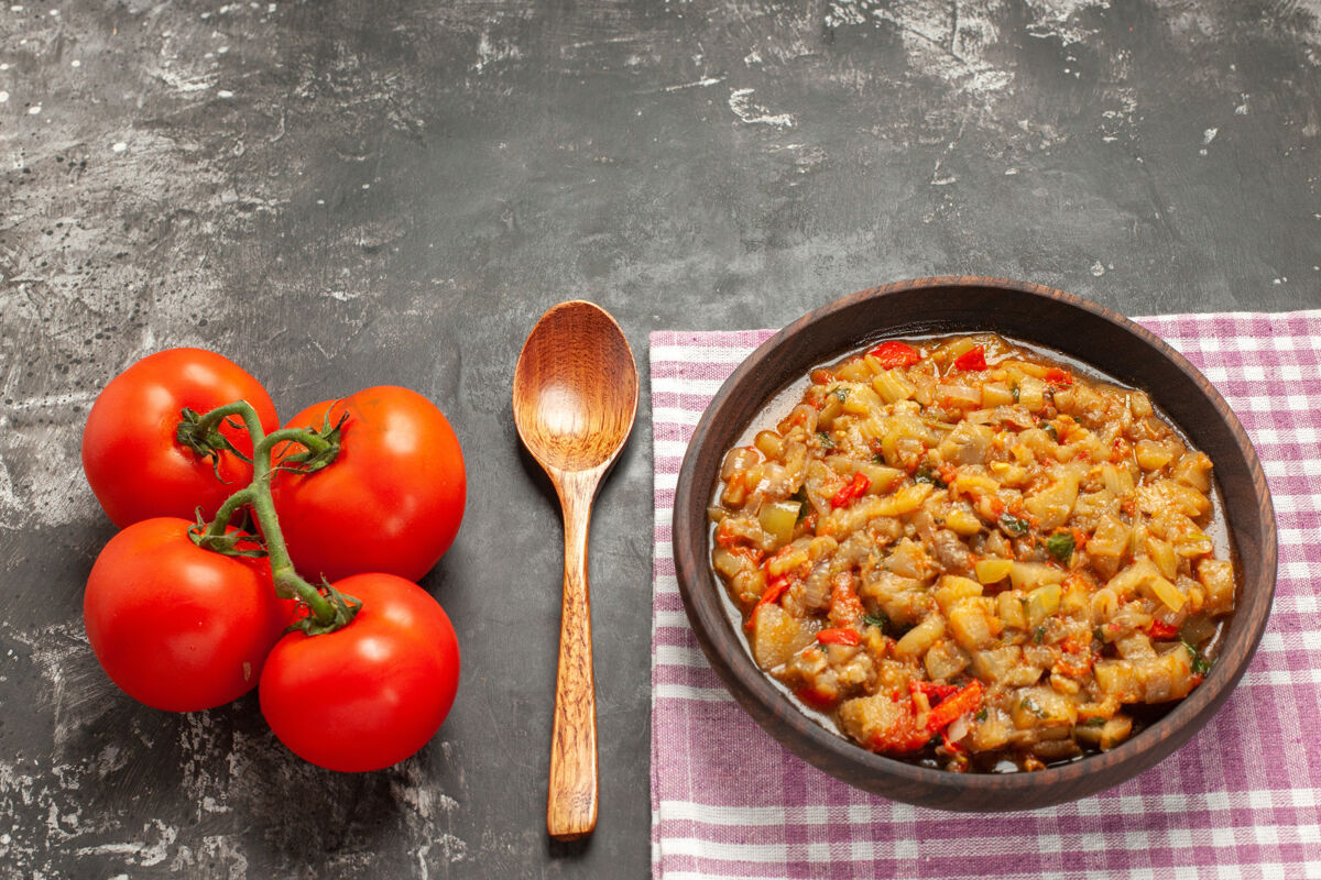 碗顶视图烤茄子沙拉在碗里一个木勺西红柿在黑暗的表面烹饪饮食勺子