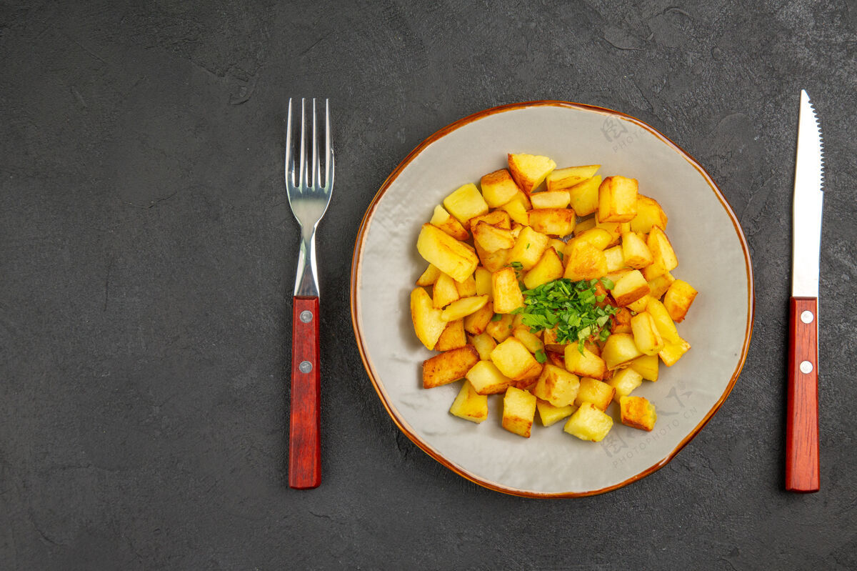 晚餐美味的炸土豆在黑暗的表面与绿色盘子里俯瞰深色里面玉米