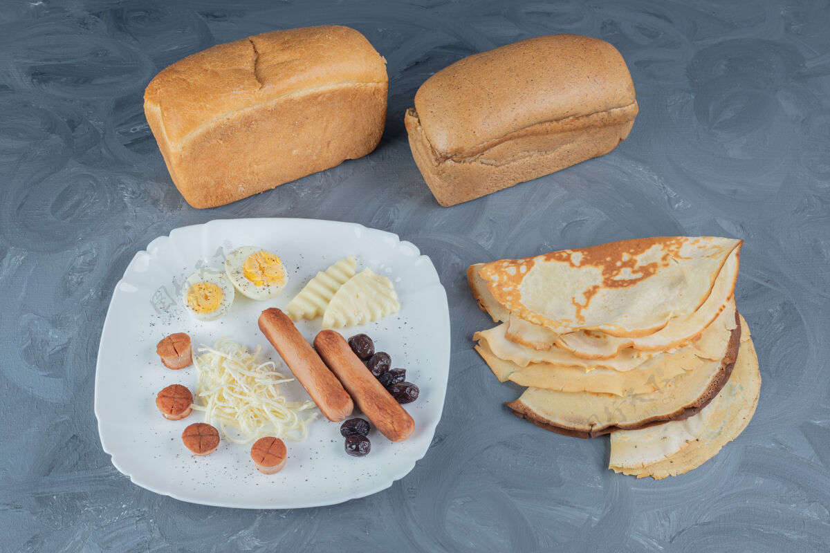 奶酪面包块和薄煎饼放在大理石桌上的早餐盘旁边美味切片薄煎饼