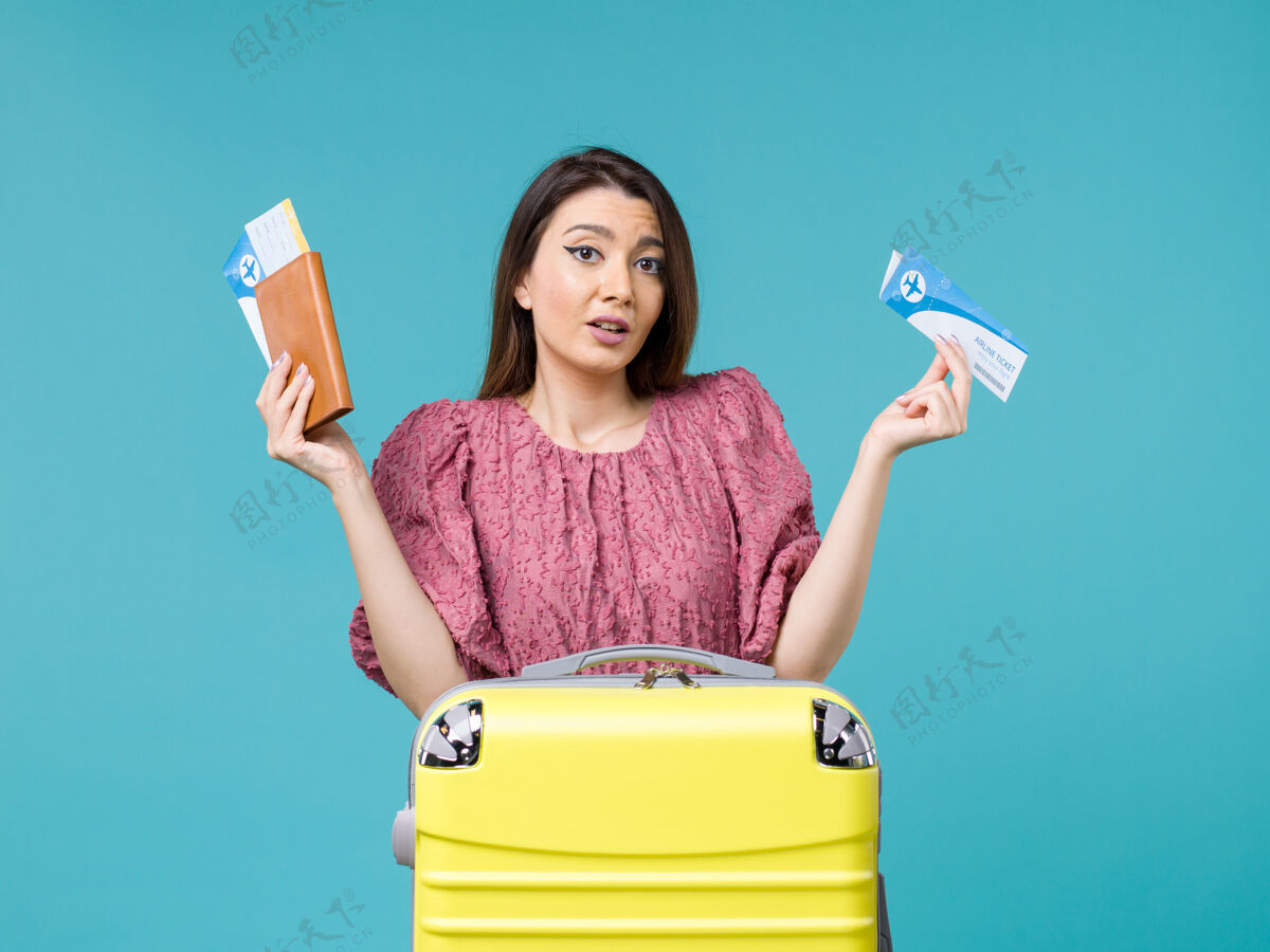 人前景度假中的女性手持蓝色背景的机票旅行海上女性旅行暑假举行前面旅程