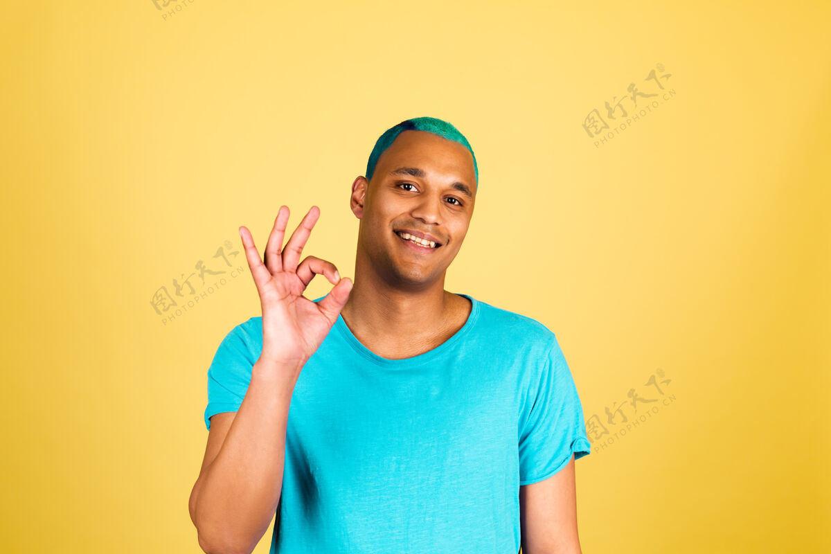 认可黑色的非洲男人在随意的黄色墙壁上快乐的看着镜头 微笑着展示ok的手势商人美国好
