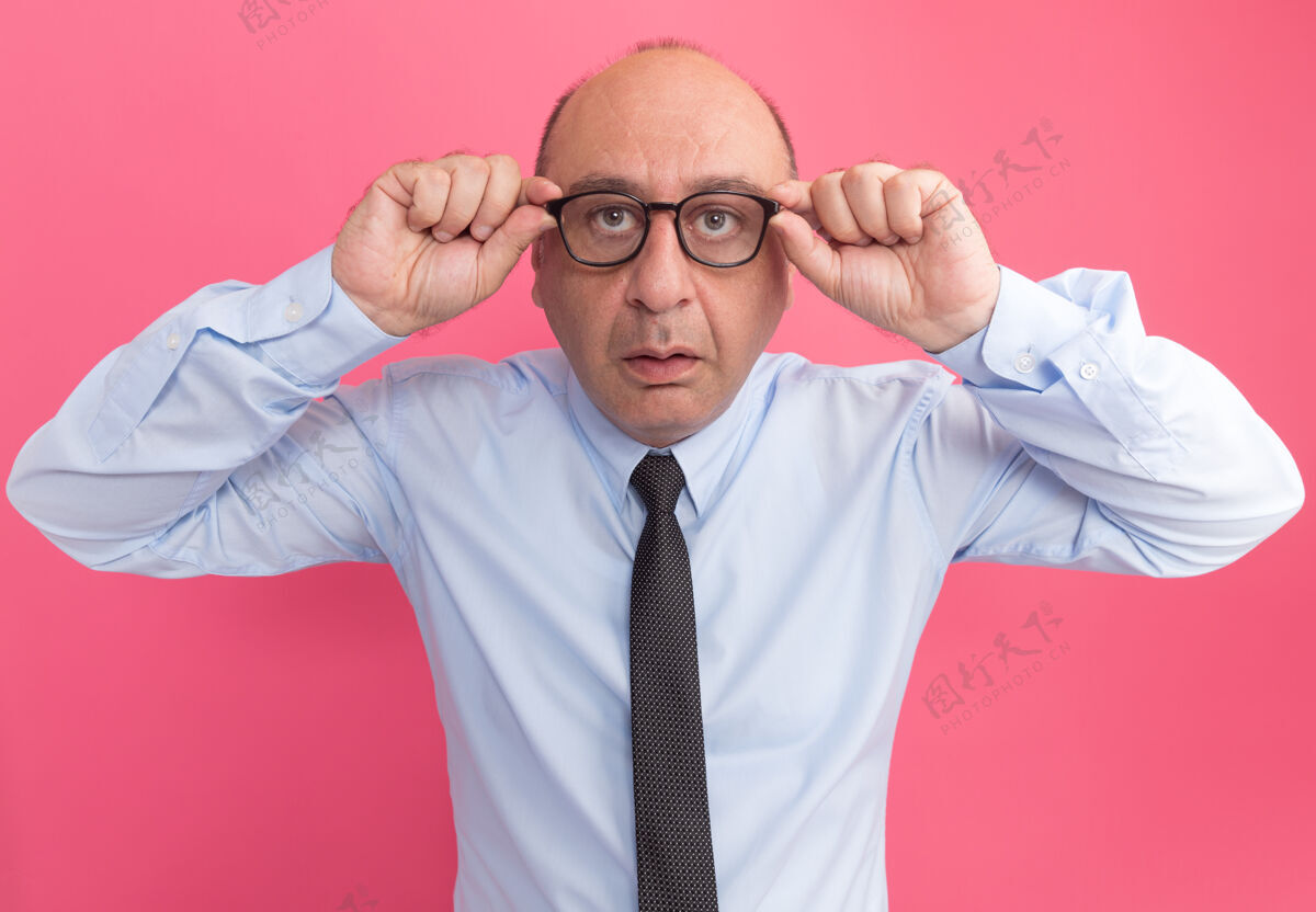 脸疑神疑鬼地看着前面的中年男子 穿着白色t恤 打着领带 戴着眼镜 隔离在粉红色的墙上感情衣服领带