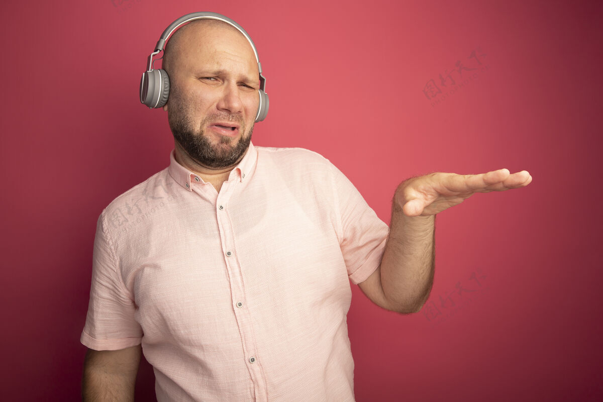 秃头未租中年秃头男子穿着粉色t恤和耳机显示大小穿显示大小
