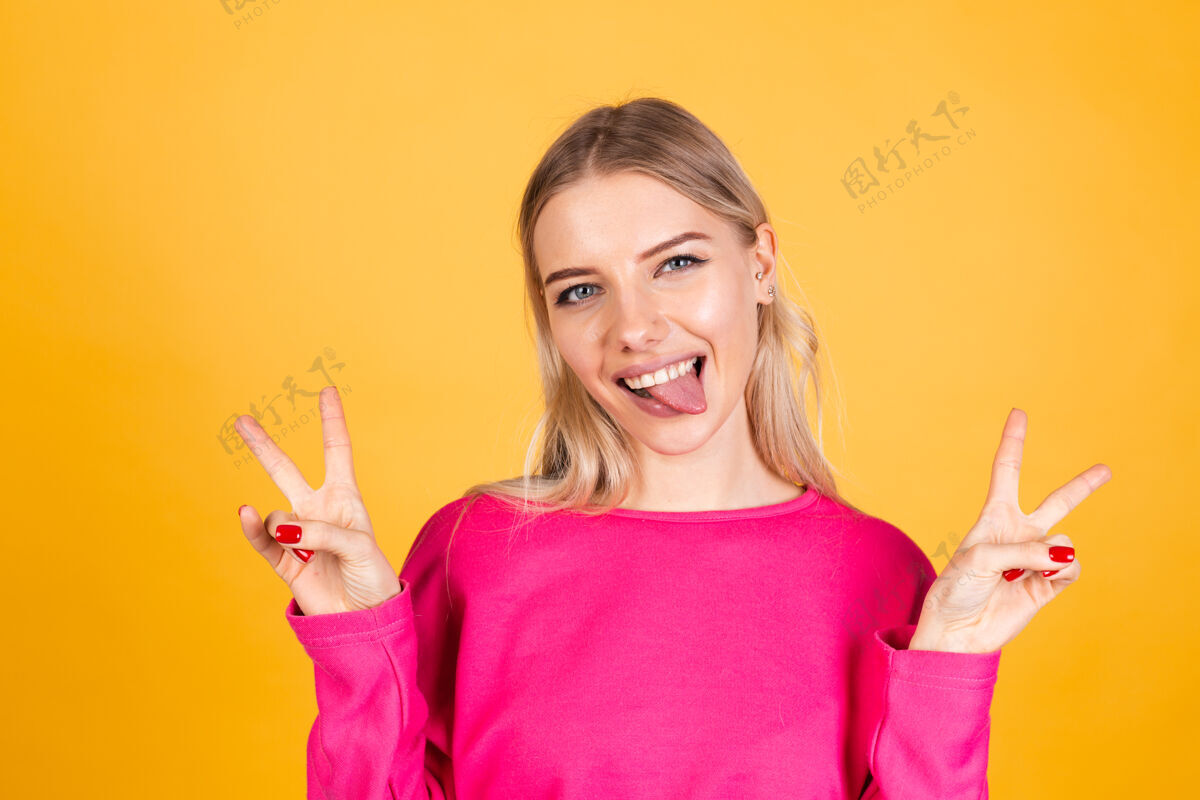 复制空间黄色墙上穿粉红色上衣的漂亮欧洲女人人乐趣手指
