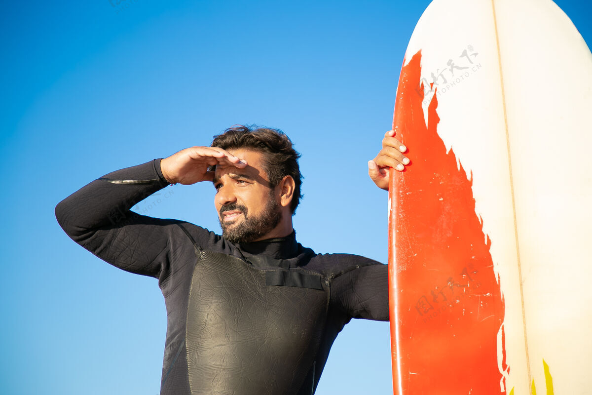 男人专注的英俊冲浪者凝视着远方海滩夏天海洋
