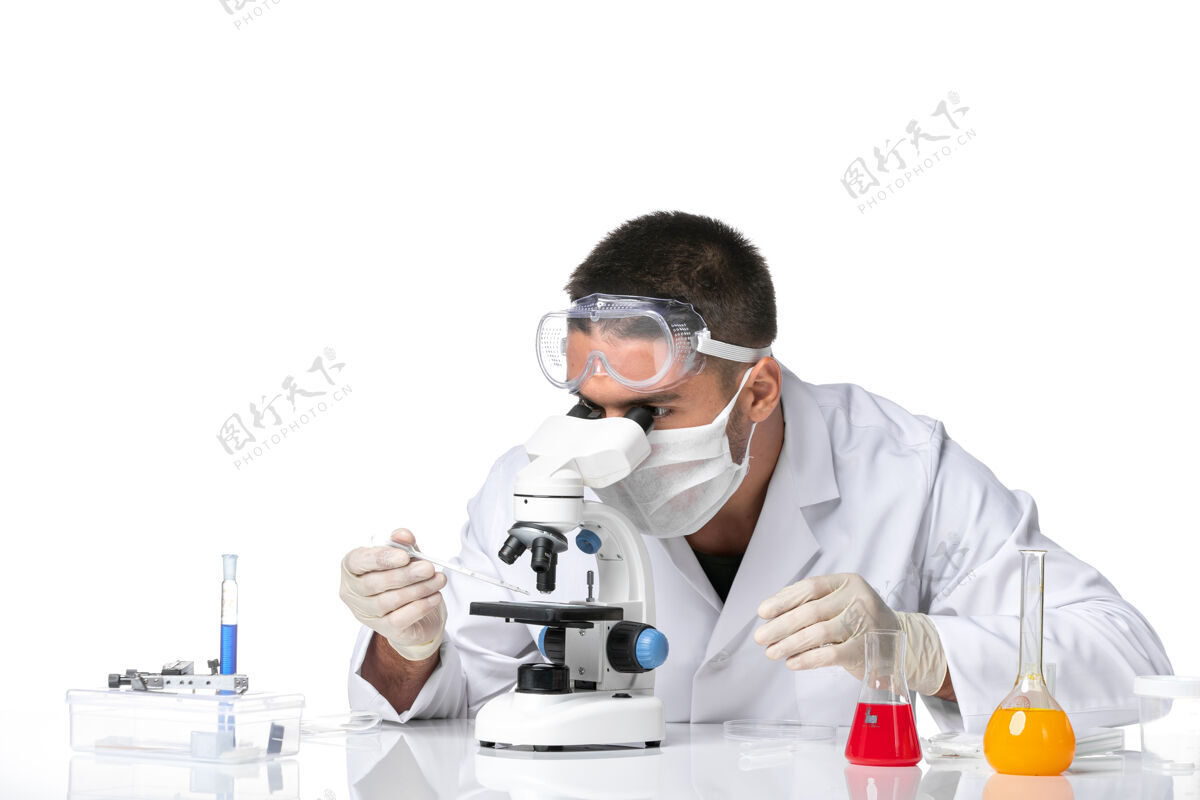 使用前视图：男医生穿着白色医疗服 戴着面罩 在空白处使用显微镜诊所病毒药
