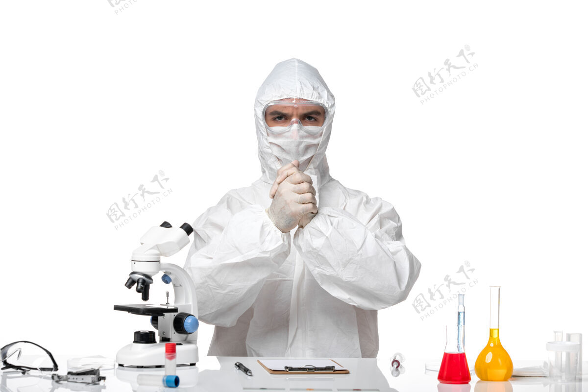 男人正面图：男医生穿着防护服 戴着口罩 因为科维德正坐在白色的桌子上雕塑流行病医疗