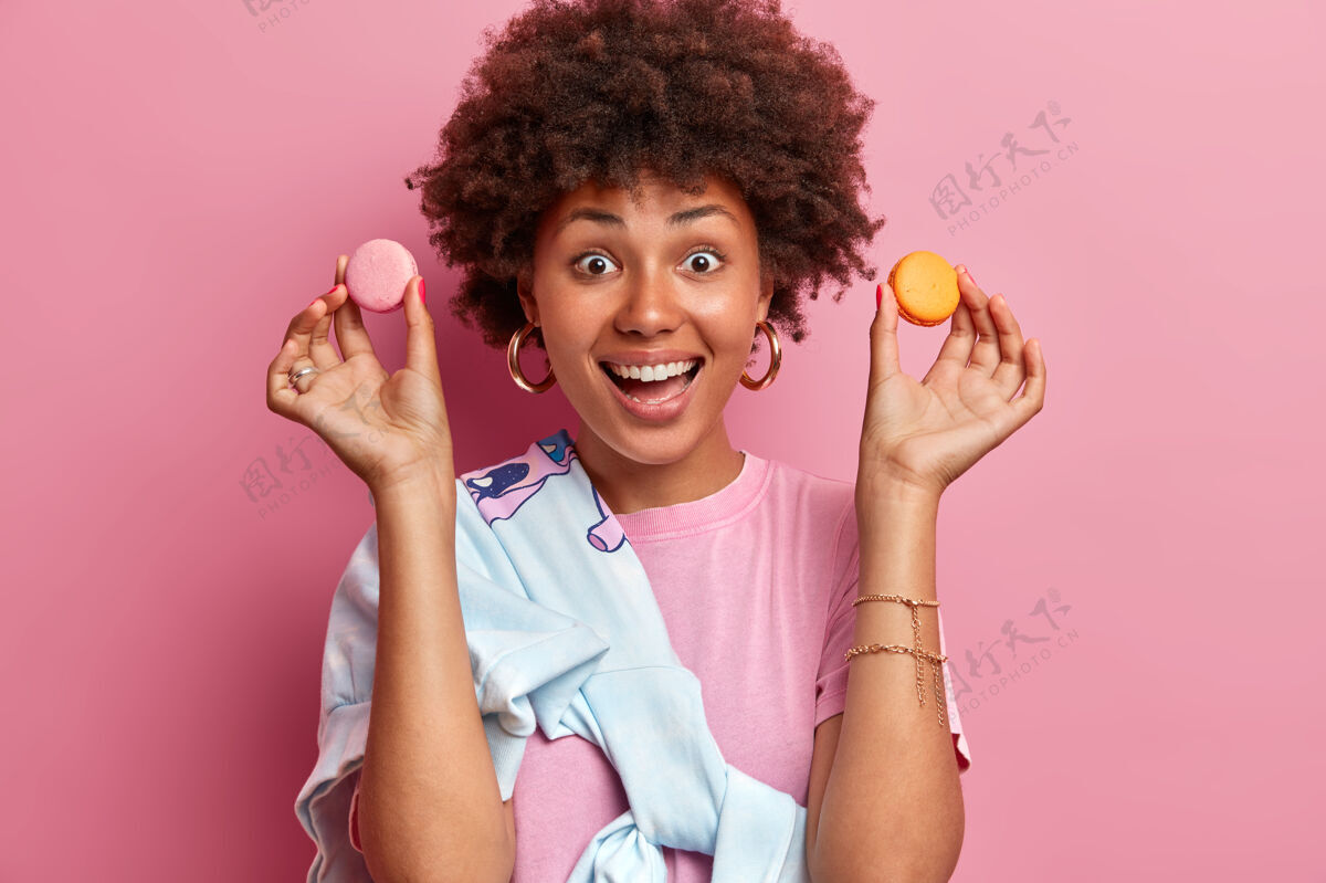 抱着快乐的非裔美国女人拿着两个杏仁饼的水平镜头正咯咯笑食物饼干好吃