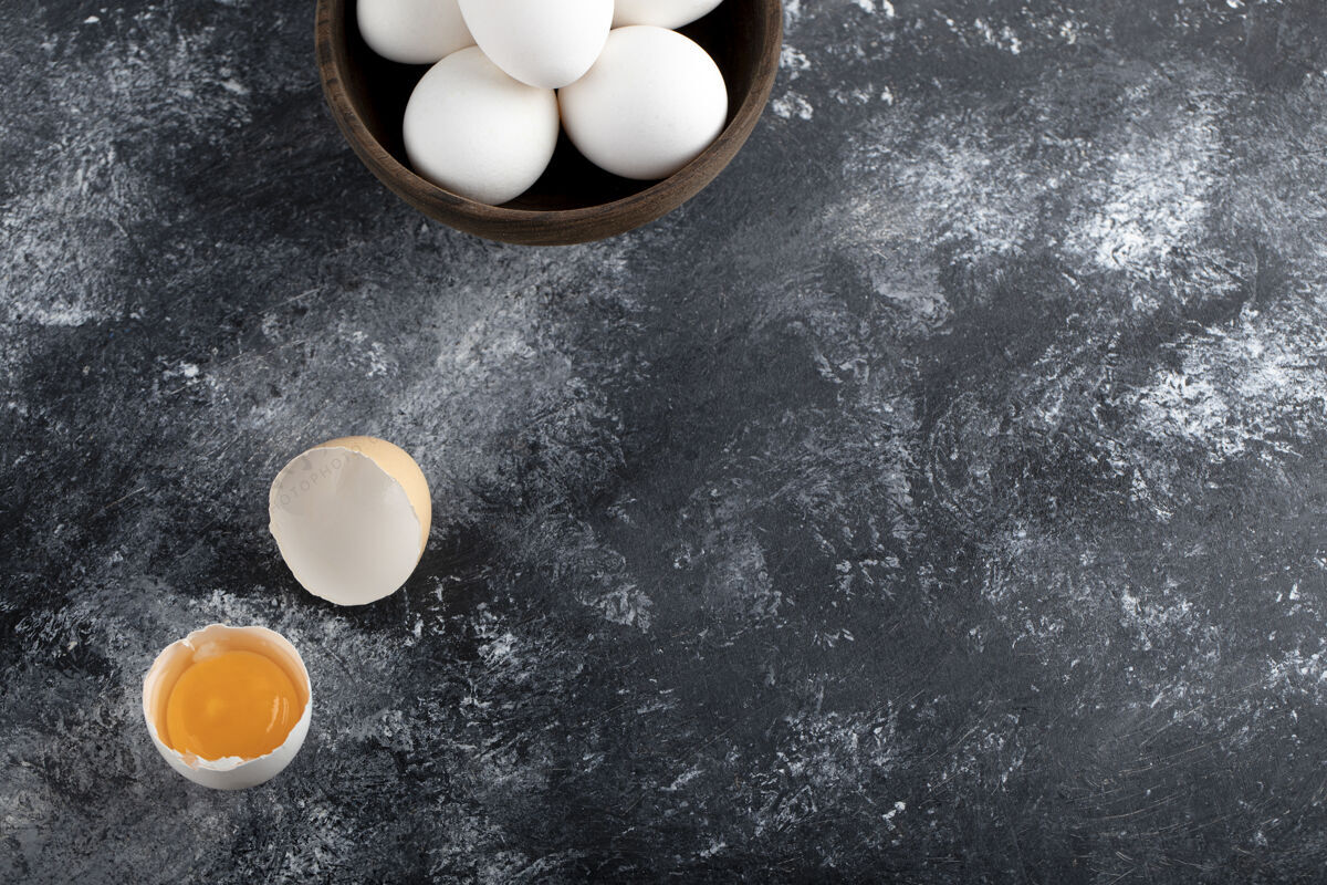 破碎在大理石表面放一碗白鸡蛋和蛋黄烹饪蛋壳美味