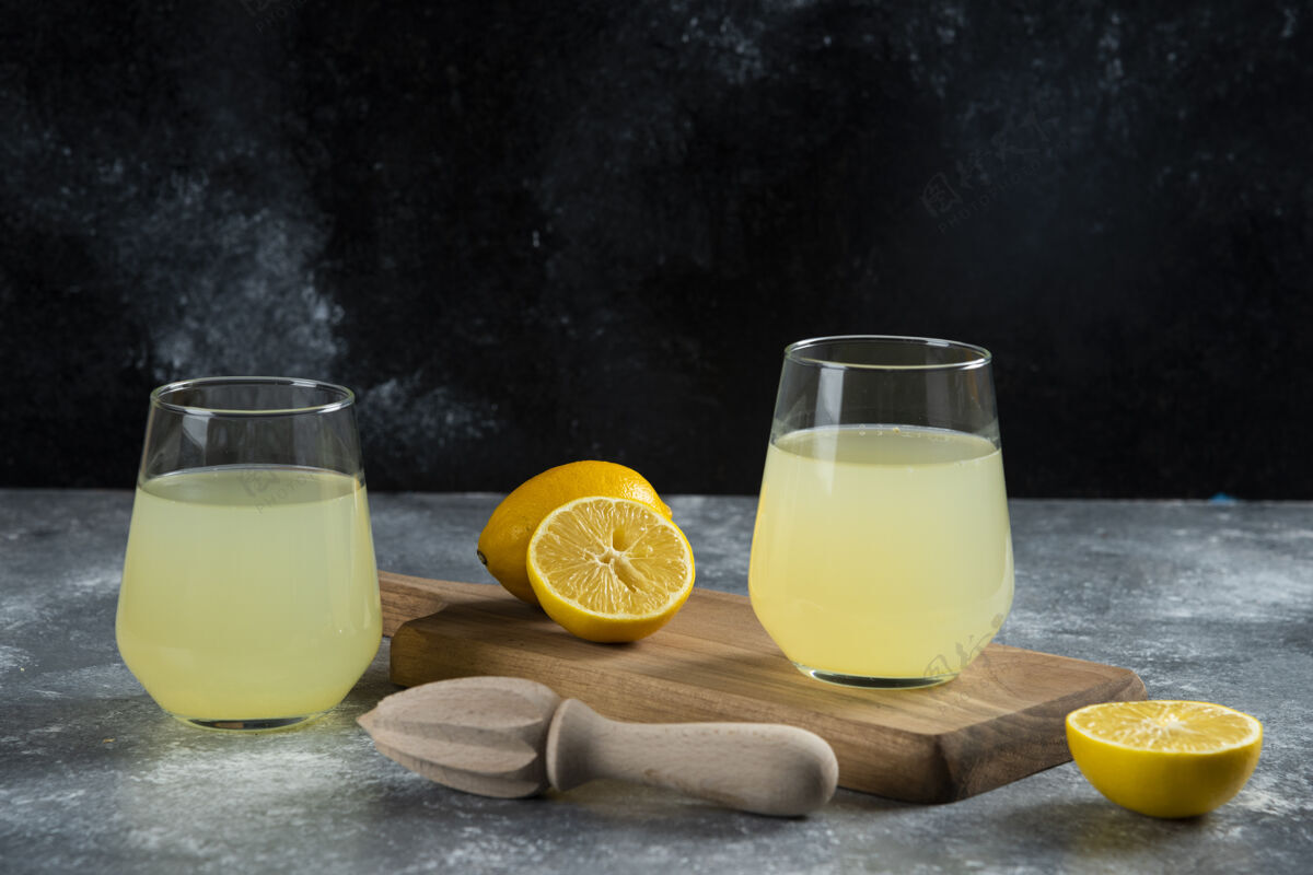 马克杯两杯新鲜柠檬汁和木铰刀新鲜的酸的柑橘