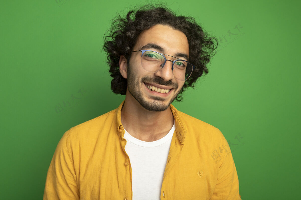 人戴着眼镜微笑的年轻帅哥的特写镜头 看着隔离在绿色墙壁上的前方表情人特写