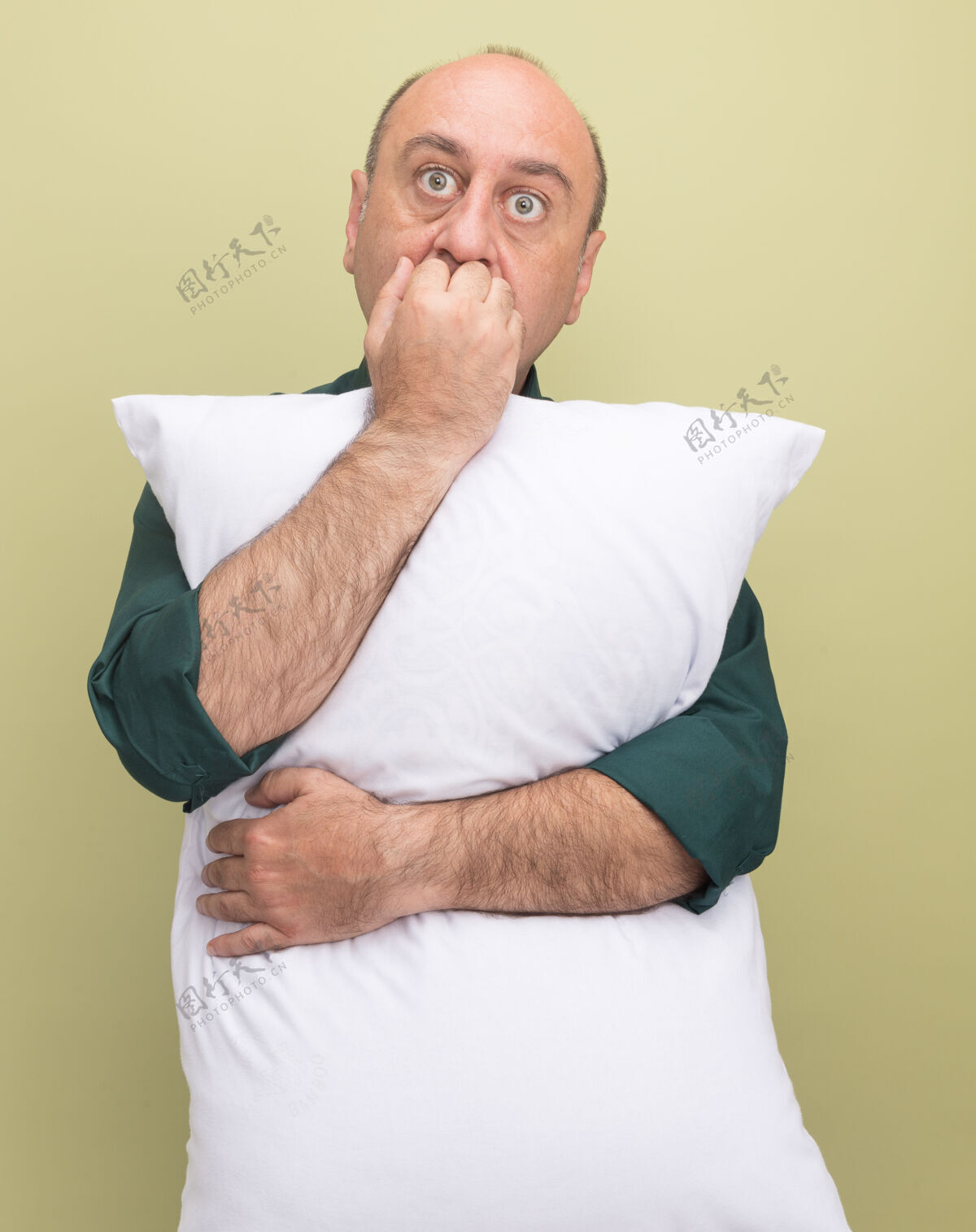 拥抱关切的中年男子穿着绿色t恤抱枕咬指甲隔离在橄榄绿的墙上中年关心枕头