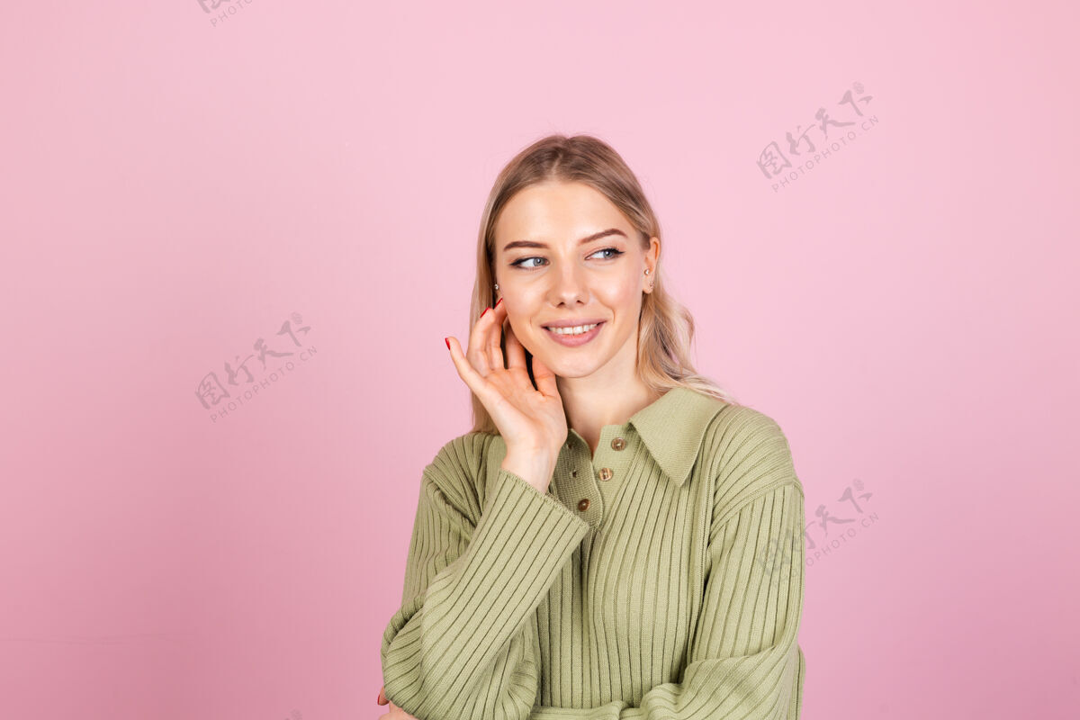 皮肤粉色墙上穿着休闲毛衣的漂亮欧洲女人欢呼年轻淑女