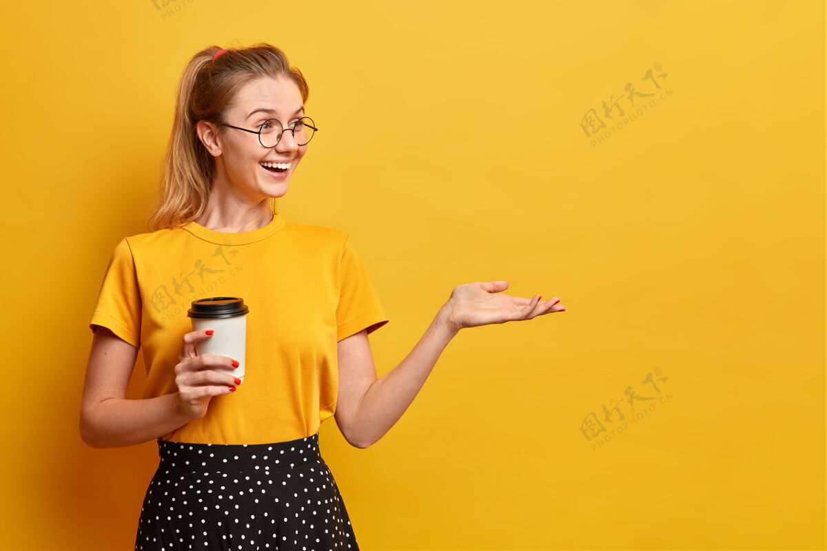 喝酒真诚积极向上的女孩用一次性杯子喝着芳香的咖啡举起手来黄色女人手