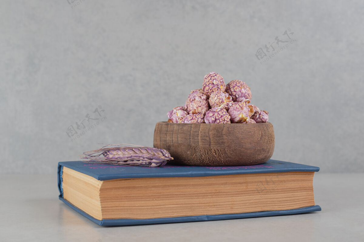 阅读在大理石背景的书上放一碗有香味的爆米花和一根紫色的麦秆背景玉米谷类