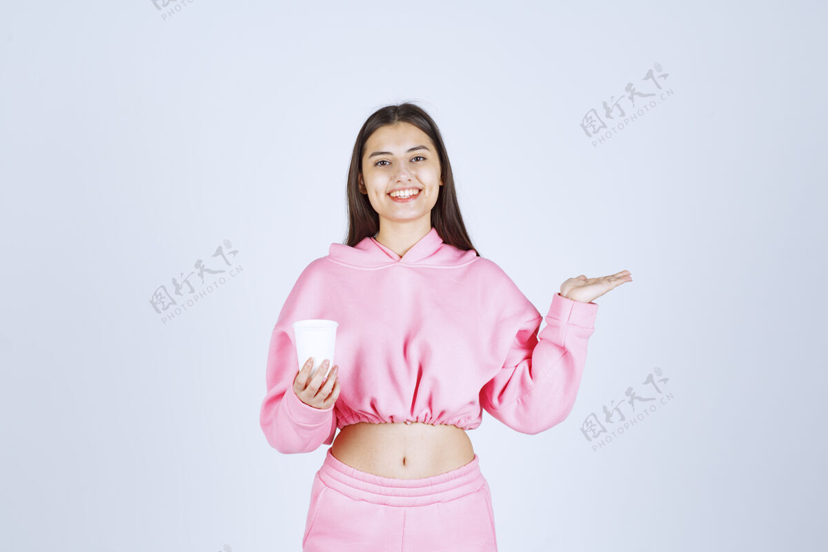女性穿着粉色睡衣的女孩拿着咖啡杯指着什么东西积极成人服装
