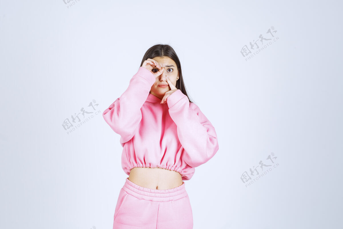 服装穿粉红色睡衣的女孩在手指间打量成人姿势隐藏