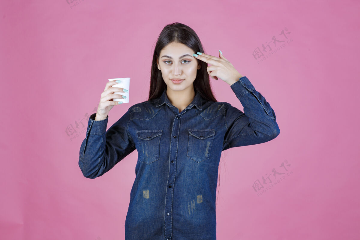 人穿着牛仔衬衫的女孩正在享受一杯一次性咖啡人茶成人
