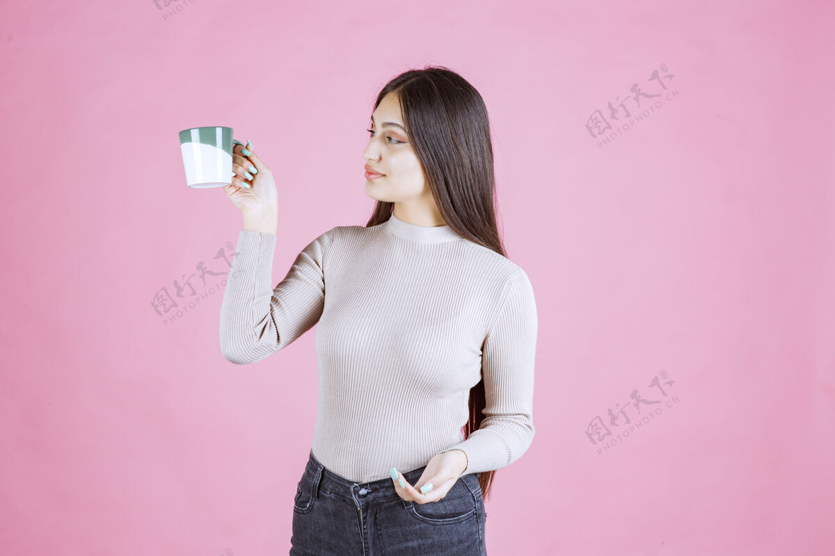卡布奇诺女孩拿着一个白绿色的咖啡杯 感觉很积极成人女人人
