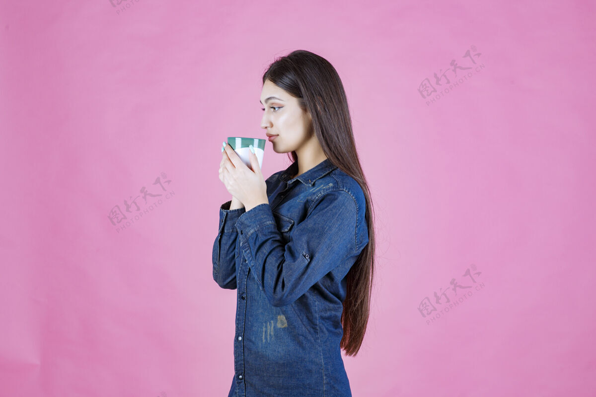 休闲女孩拿着一个白绿色的咖啡杯 闻着女人人商业