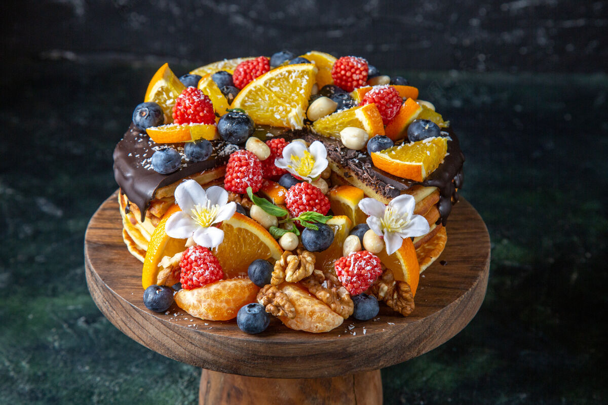 蛋糕正面是美味的水果蛋糕和巧克力糖浆 放在黑色的圆木桌上水果浆果食物