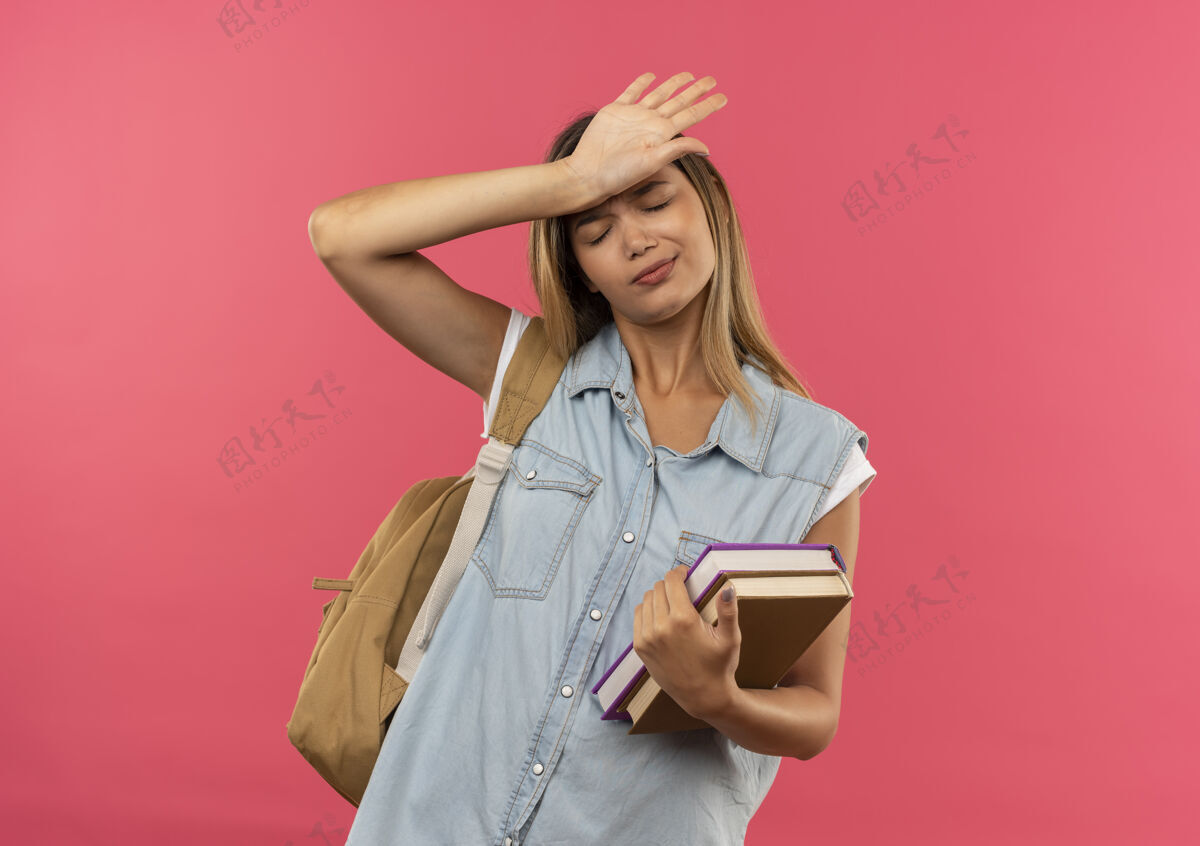 额头疲惫的年轻漂亮的女学生 背着书包 手放在额头上 闭着眼睛 隔离在粉色背景上 留着复印空间年轻包漂亮