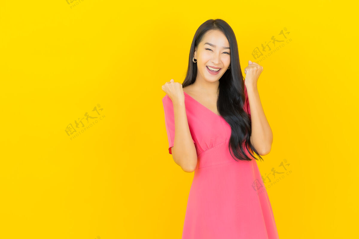 中国人黄色墙壁上 美丽的亚洲年轻女子身着粉色连衣裙微笑的画像卷发女性黑发