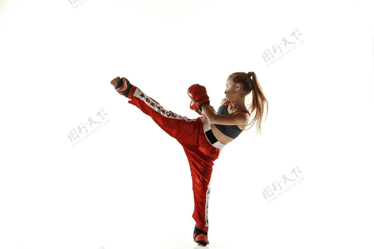 运动员年轻的女子跆拳道拳击手在白墙上孤立地训练穿着红色运动服的白人金发女孩练习武术运动的概念 健康的生活方式 运动 动作 青春战斗长跆拳道
