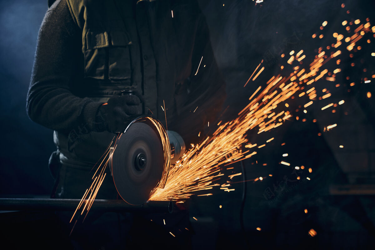 金属加工戴着防护手套的工人用火花打磨金属制造工厂工具