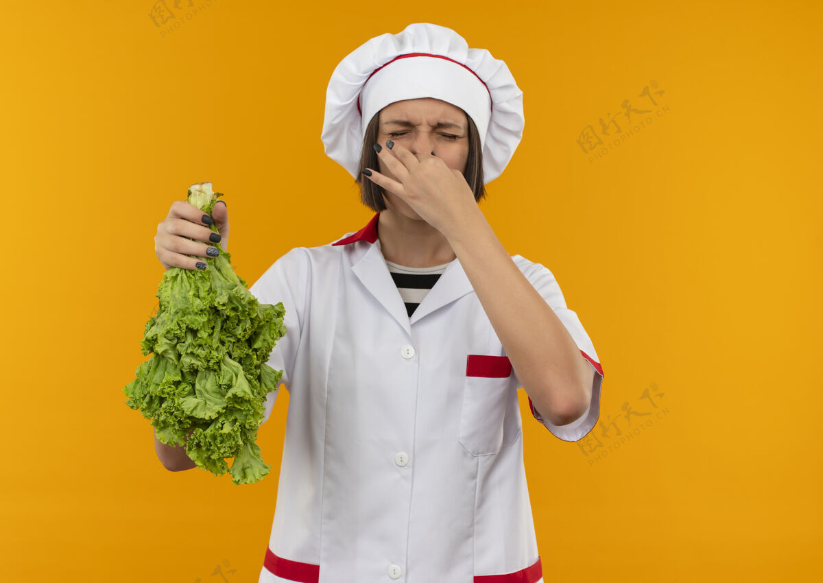 持有年轻的女厨师穿着厨师制服 手里拿着莴苣 闭着眼睛 鼻子里只剩下橘子味厨师封闭女性
