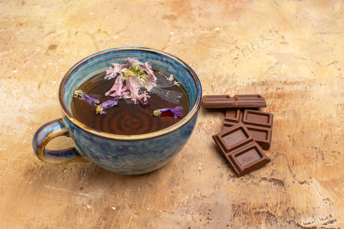 热一杯热凉茶和巧克力棒在混合色桌子上的水平视图草药桶产品
