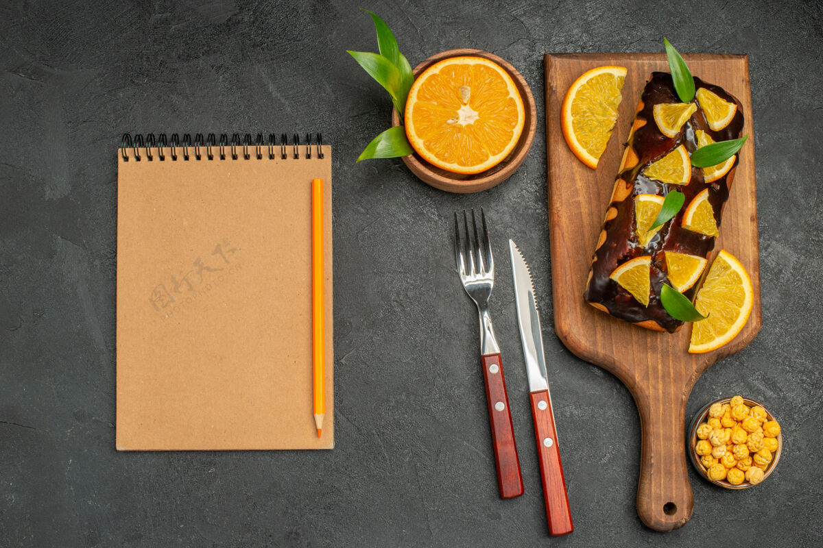 叶放上松软的蛋糕 用叶子切柠檬 把笔记本放在深色的桌子上板刀笔记本