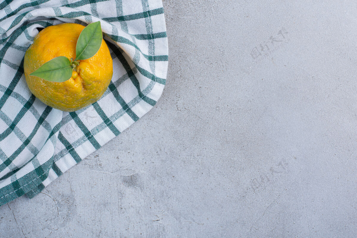天然在大理石背景上的毛巾上放一个橘子健康美味配料
