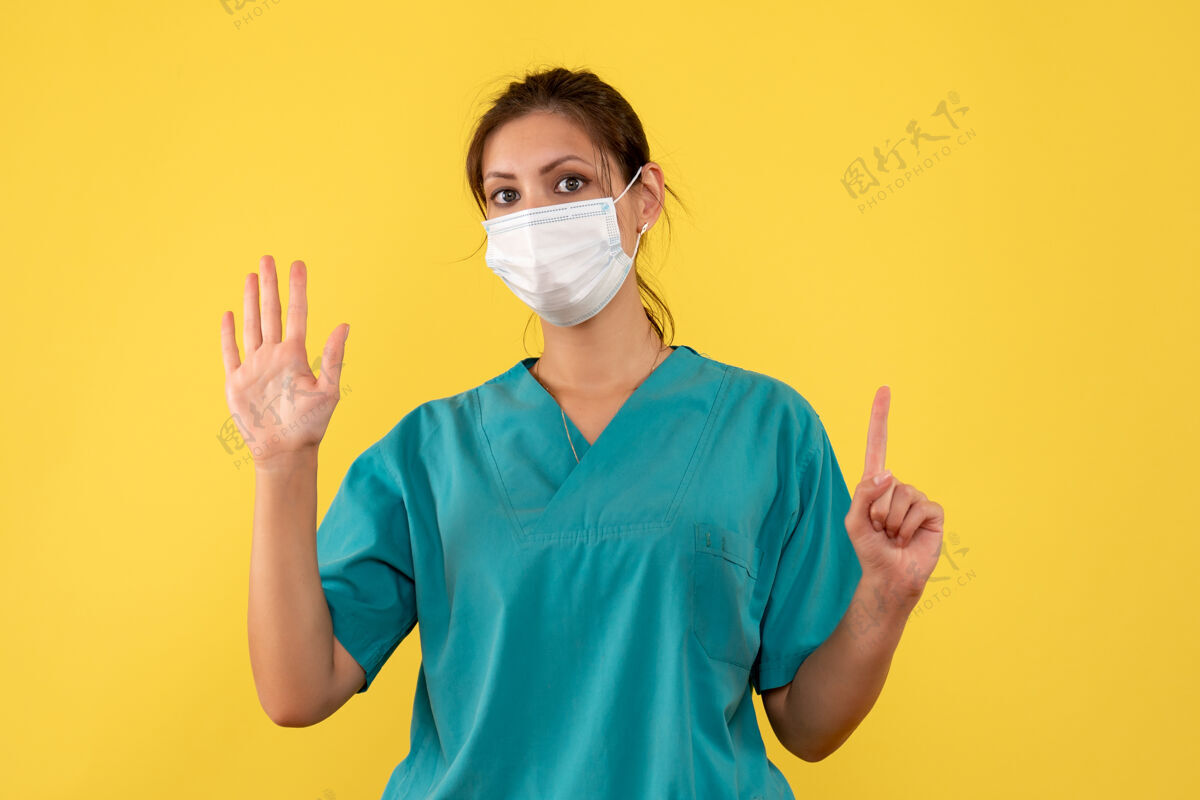 大流行正面图黄色背景上穿着医用衬衫和无菌口罩的女医生消毒医疗人