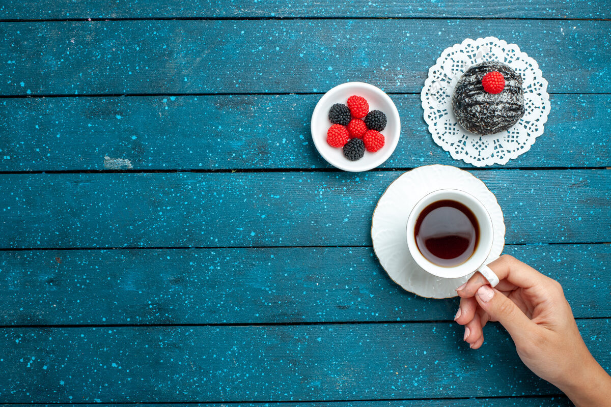 饼干俯瞰美味的巧克力球和一杯茶在一个蓝色的乡村书桌上茶蛋糕饼干饼干甜帽子桌子生的