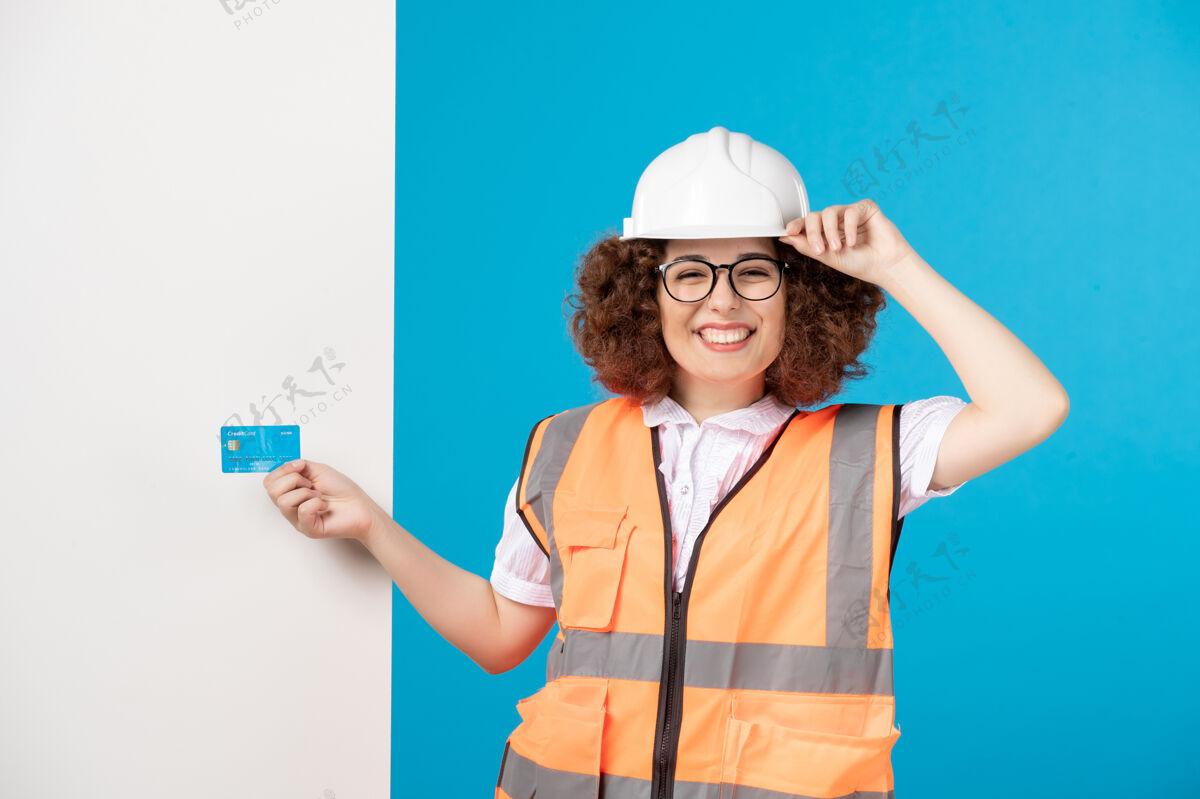 男人穿着制服的女工正对着蓝色墙上的蓝色信用卡女工人前面帽子