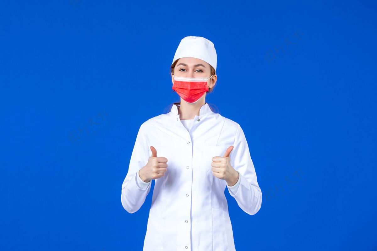 大流行正面图身着医疗服的年轻护士 蓝色墙上戴着红色防护面具医疗红色蓝色