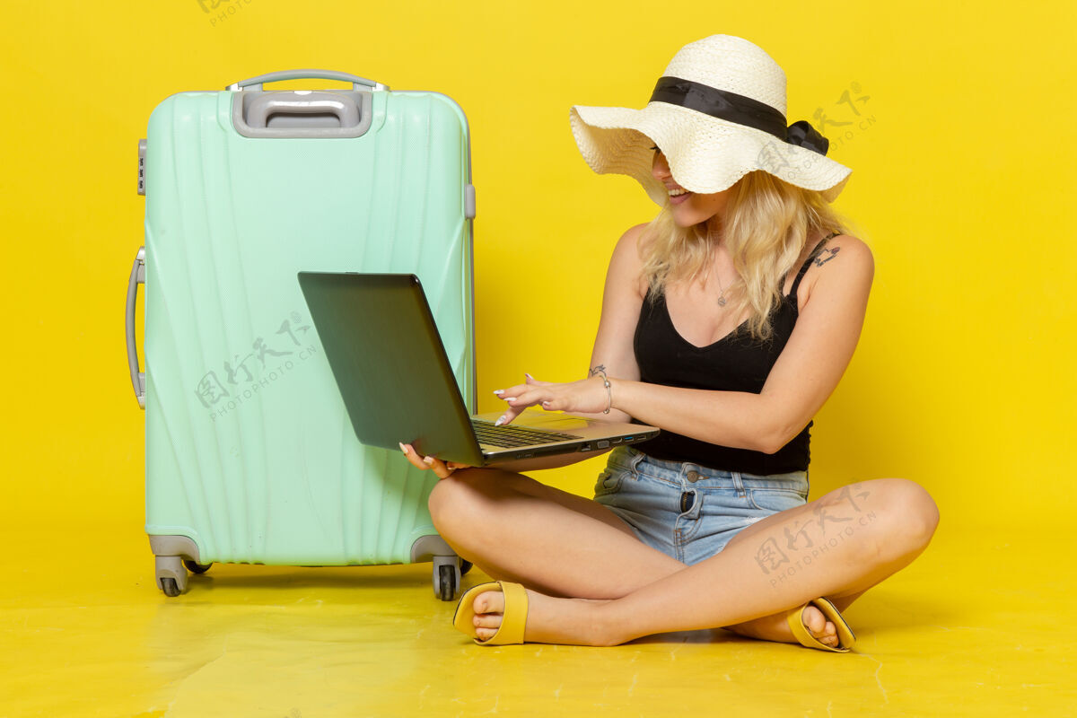 年轻正面图年轻女性在黄墙上使用笔记本电脑女孩旅行旅行旅行旅行旅行太阳视野笔记本电脑书桌