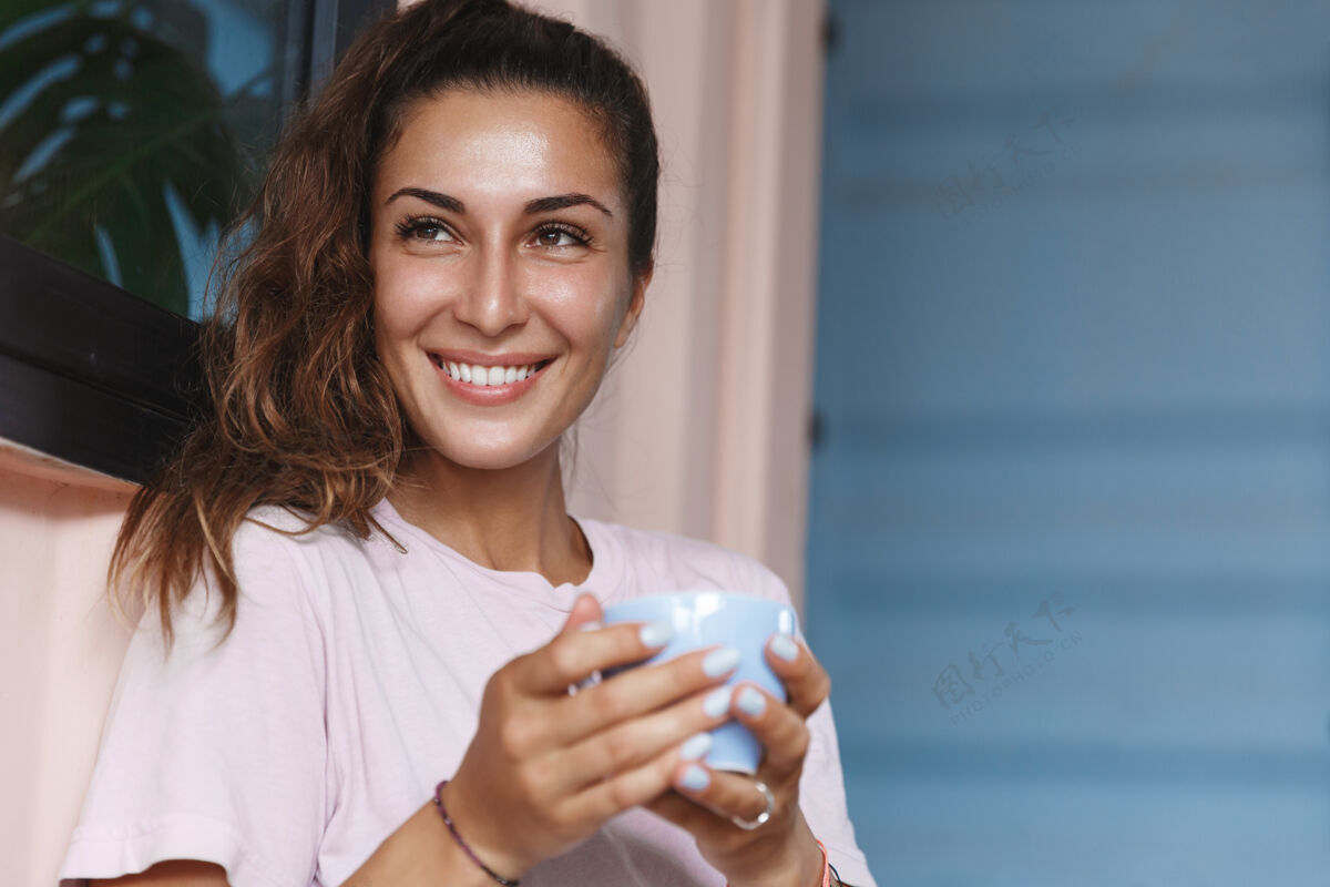 享受一个轻松微笑的女孩在门廊喝茶的特写照片舒适像家一样杯子