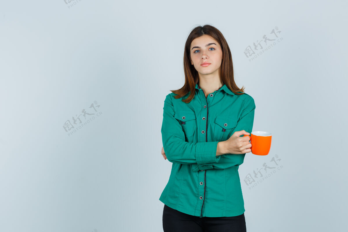 女性年轻的女士拿着一杯橘色的茶 穿着衬衫 看起来很自信 正对着前方信心家庭清洁