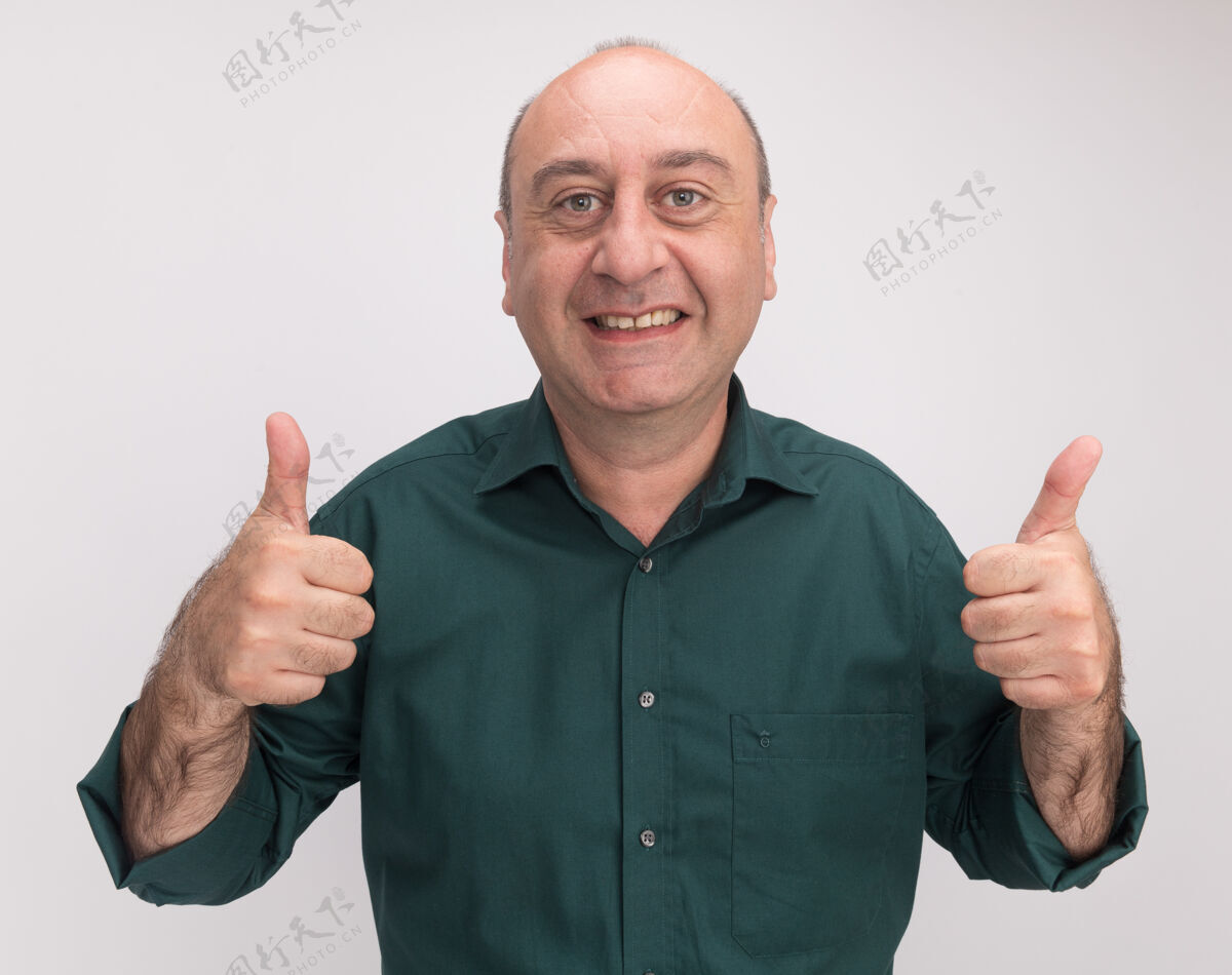 拇指微笑的中年男子身穿绿色t恤 竖起大拇指孤立地站在白色的墙上T恤微笑中年