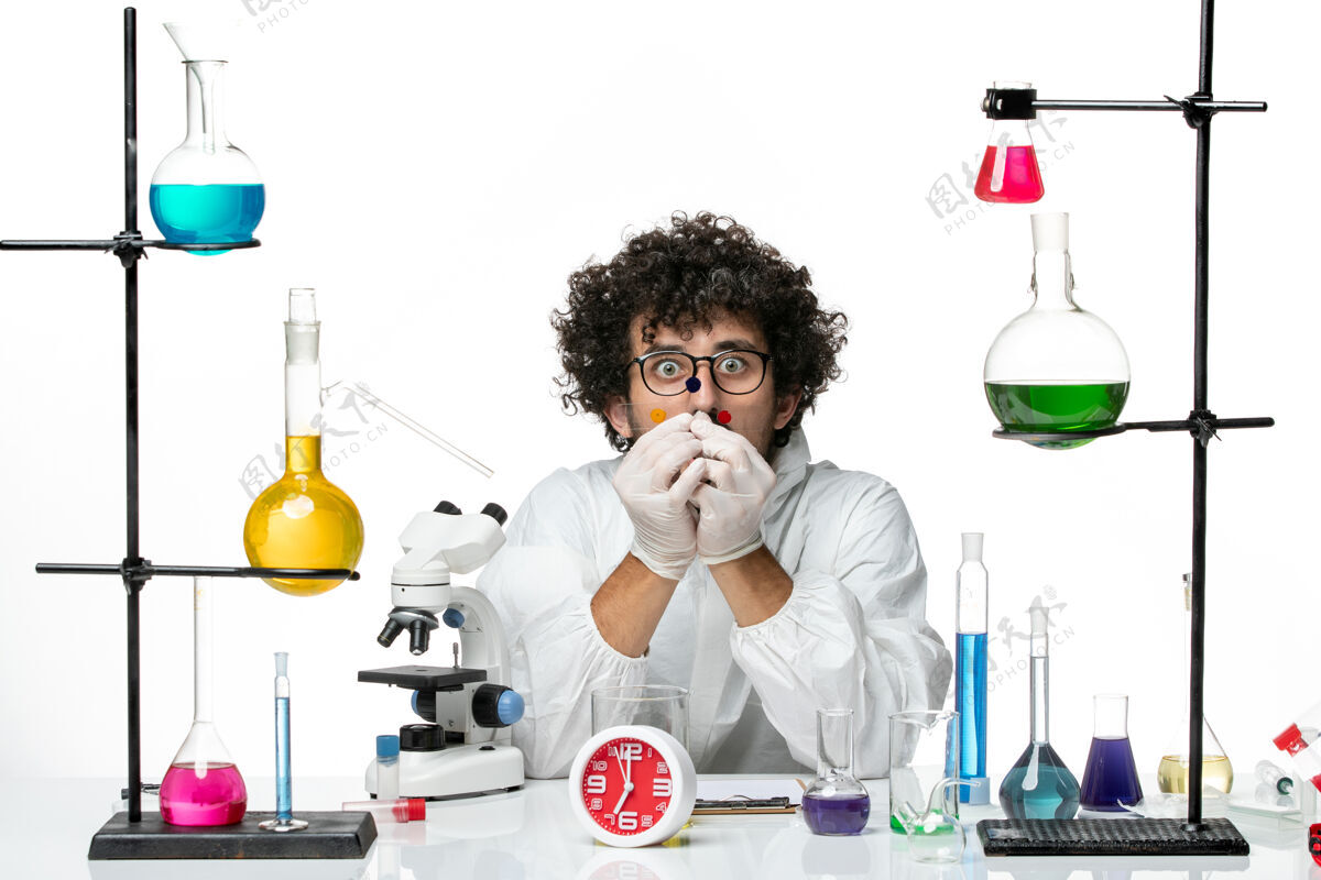 科学正面图身着特殊套装的年轻男性科学家围着桌子工作 在白墙上摆着解决方案套装解决方案实验室