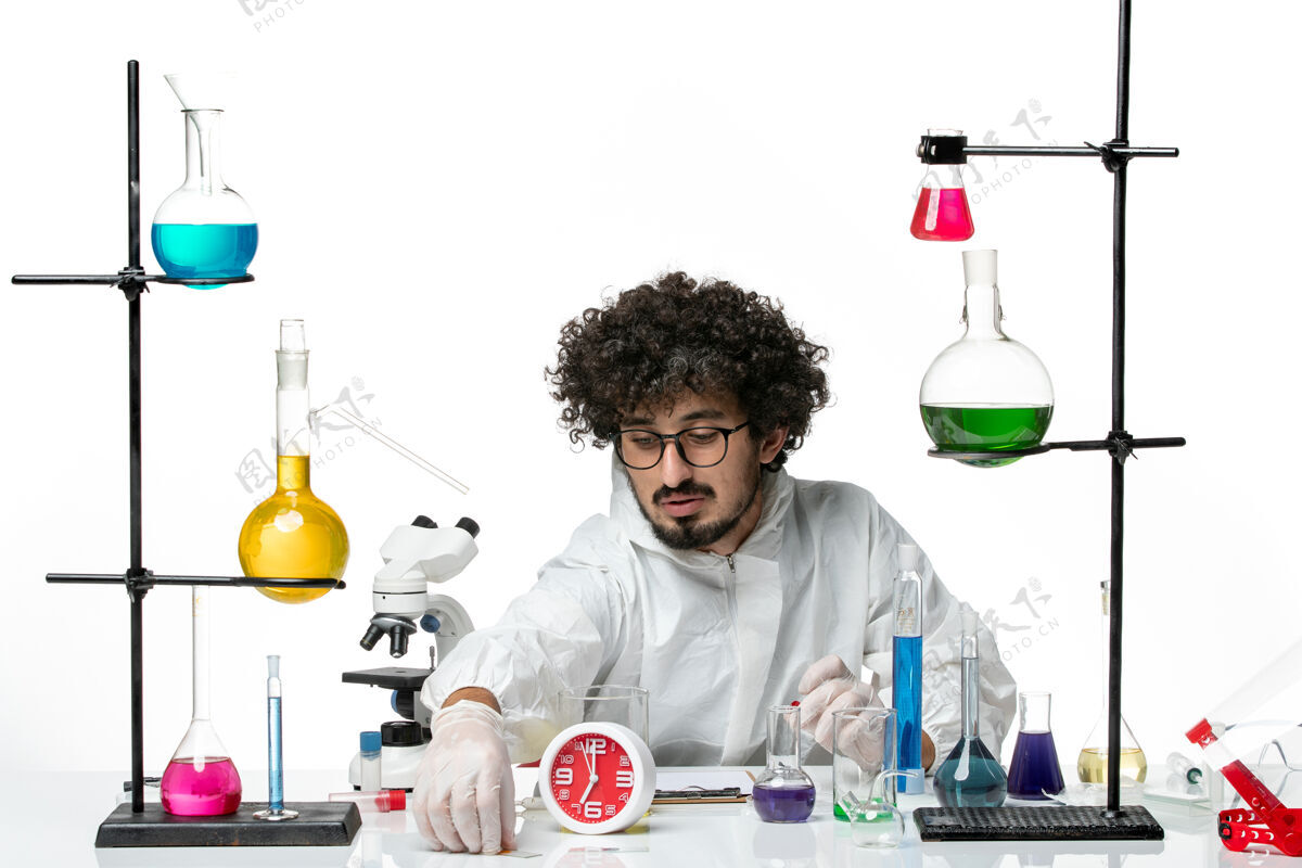 实验室白壁上工作过程中身着特殊服装的年轻男科学家的正面图化学实验室烧杯