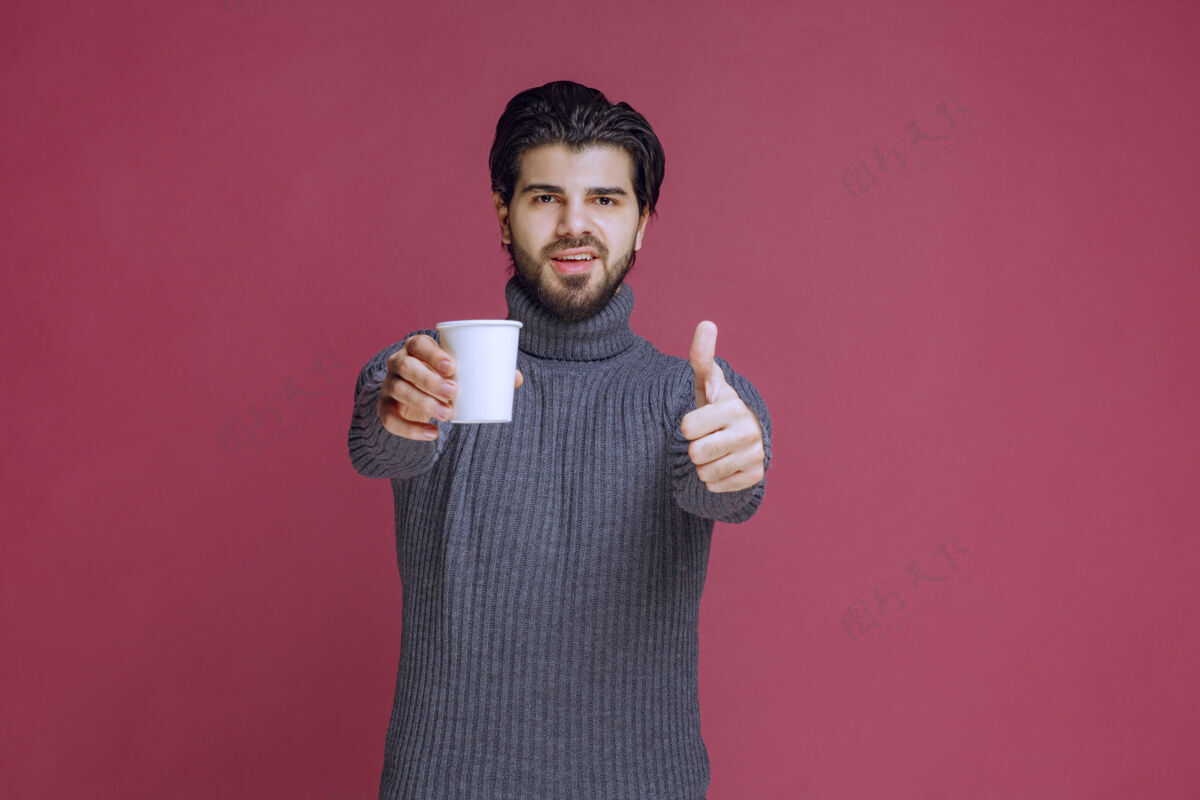 美味男人拿着一个一次性咖啡杯 做着享受的手势模特人休闲