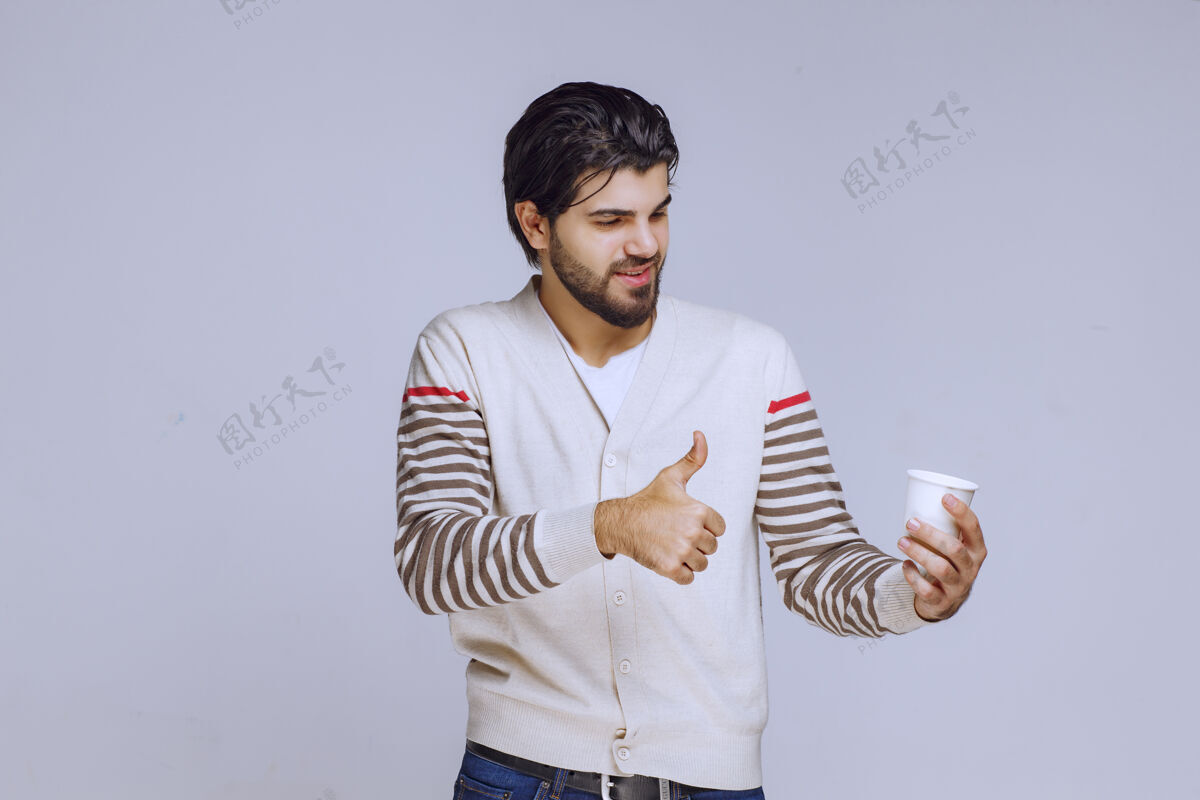 能量一个穿着白衬衫的男人拿着一个咖啡杯享受着它员工年轻男性