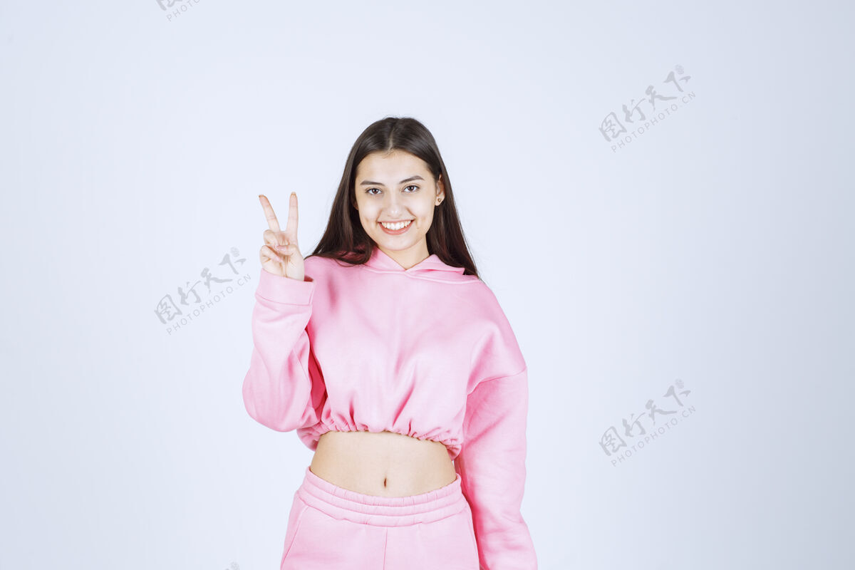 年轻人穿粉红色睡衣的女孩感到高兴 并显示积极的手势友谊年轻工人